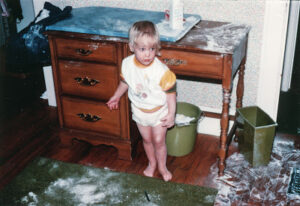 Two-year-old standing in a huge mess made from baby powder