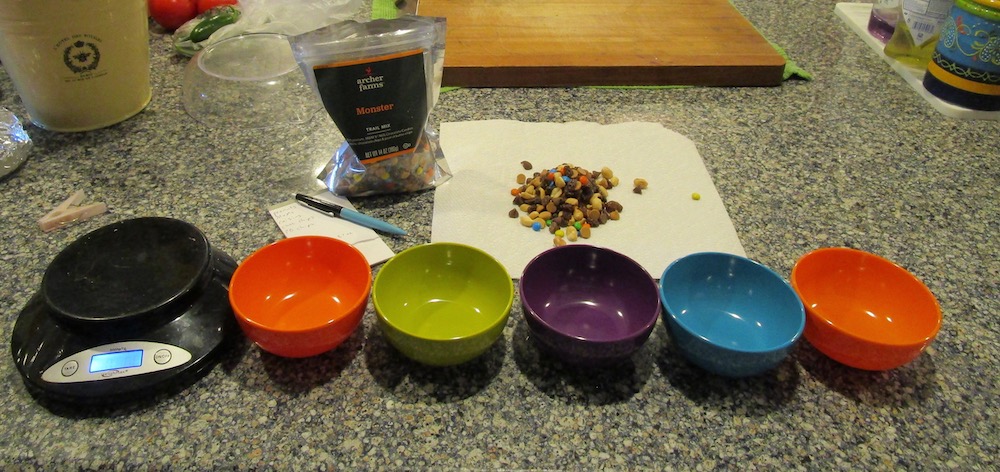 a row of bowls and a pile of trail mix ready to sort